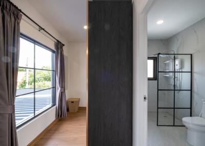 A bedroom with curtains and a window adjacent to a modern bathroom