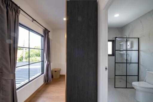 A bedroom with curtains and a window adjacent to a modern bathroom