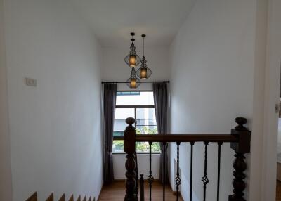 Staircase landing with hanging lights and window