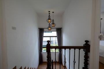 Staircase landing with hanging lights and window