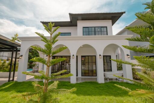 Front view of a modern two-story house with arches and a lawn