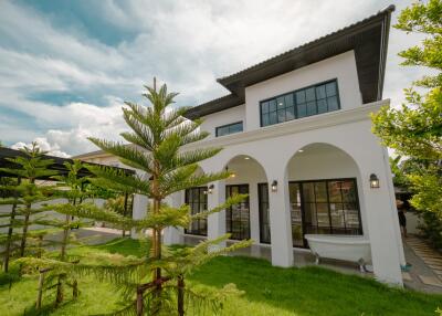 modern white two-story house with large windows and green lawn