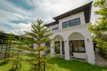 modern white two-story house with large windows and green lawn