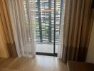 Living area with a sliding door leading to a balcony with wooden blinds