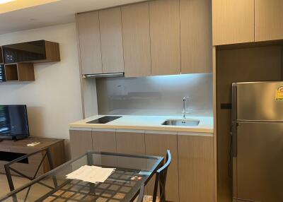 Modern kitchen area with dining table, fridge, and cabinetry