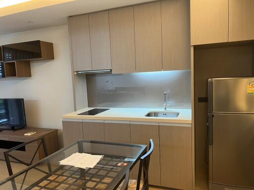 Modern kitchen area with dining table, fridge, and cabinetry