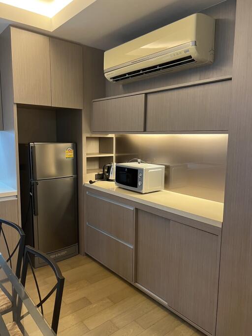 Modern kitchen with wooden cabinets, built-in microwave, refrigerator, and air conditioner