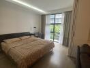 Modern bedroom with a large bed, desk, and a view through a window with curtains