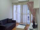 Living room with sofa, coffee table, TV, and balcony view