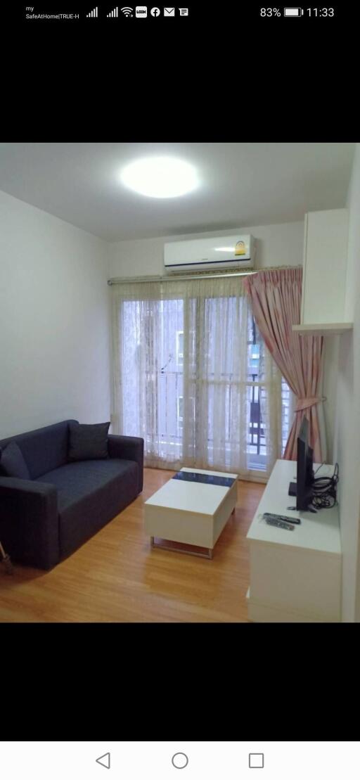 Living room with sofa, coffee table, TV, and balcony view