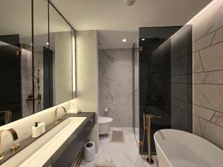 Modern bathroom with marble tiles, dual sinks, shower area, and free-standing bathtub