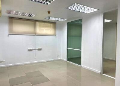 Empty office space with tiled floor and fluorescent lighting