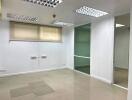 Empty office space with tiled floor and fluorescent lighting