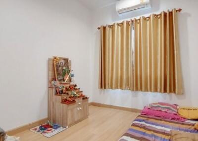 Bedroom with a single bed, window with curtains, and a small altar.