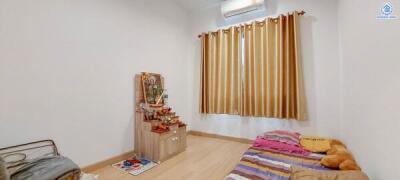 Bedroom with a single bed, window with curtains, and a small altar.