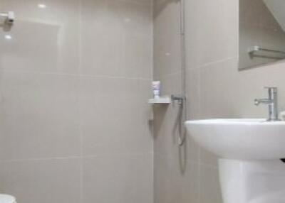 Modern bathroom with tiled walls and floor, featuring a shower, sink, and toilet