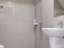 Modern bathroom with tiled walls and floor, featuring a shower, sink, and toilet