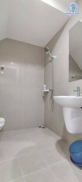 Modern bathroom with tiled walls and floor, featuring a shower, sink, and toilet