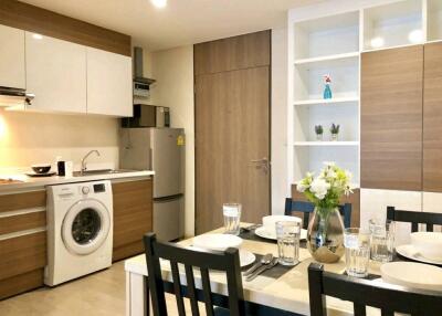 Modern kitchen and dining area with wooden cabinets, washing machine, fridge, table and chairs