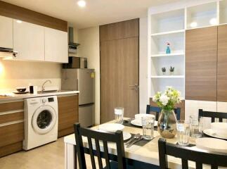 Modern kitchen and dining area with wooden cabinets, washing machine, fridge, table and chairs