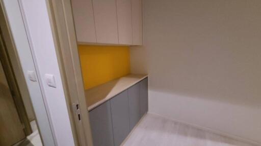 Compact kitchen area with cabinets and yellow backsplash