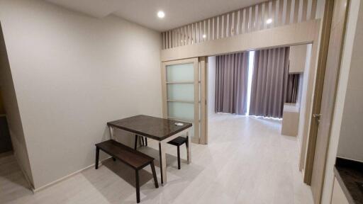 Modern dining area with a table and two benches adjacent to a living space