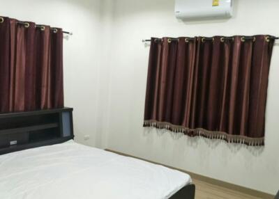 A modern bedroom with a bed and windows covered with brown curtains