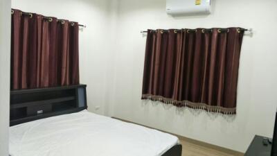 A modern bedroom with a bed and windows covered with brown curtains