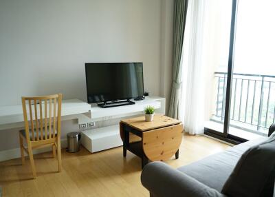 Living room with TV, desk, and balcony access