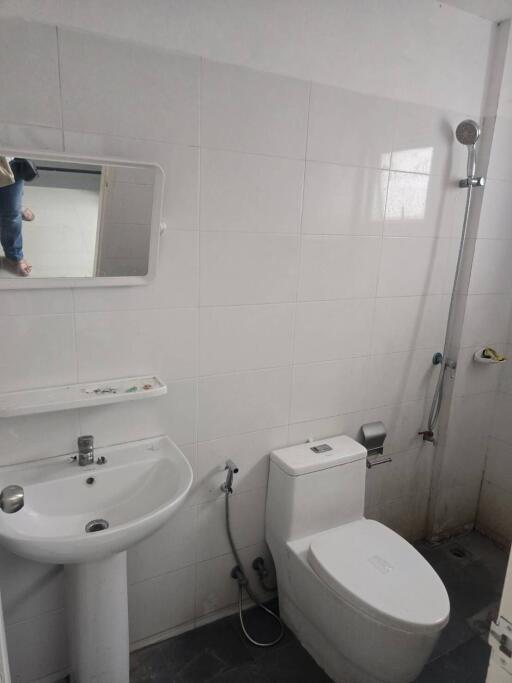 A bathroom with a sink, toilet, mirror, and a shower.