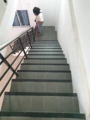 Indoor staircase with black railings leading to an upper floor