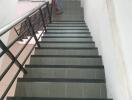 Indoor staircase with black railings leading to an upper floor