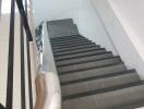 View of an indoor staircase with tiled steps and metal railings