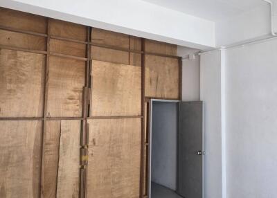 Unfurnished room with wooden wall panels and a grey door