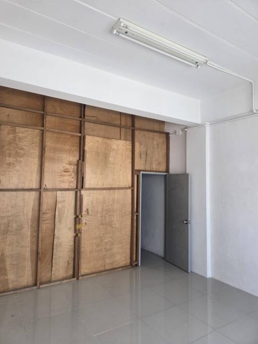 Unfurnished room with wooden wall panels and a grey door