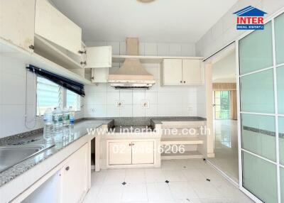 Well-lit kitchen with white cabinets and granite countertops