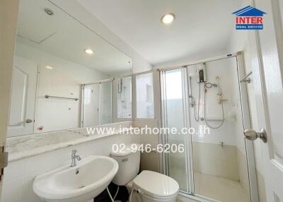 Bathroom with glass shower, white fixtures, and large mirror