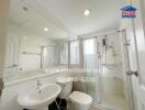 Bathroom with glass shower, white fixtures, and large mirror