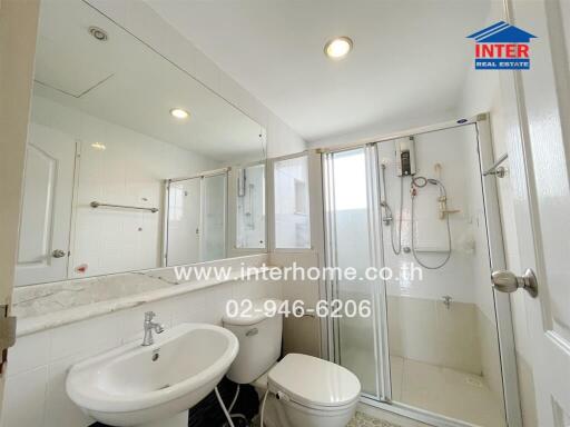 Bathroom with glass shower, white fixtures, and large mirror