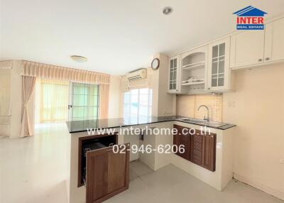 Modern kitchen with upper and lower cabinets, integrated sink, and pass-through window to living area