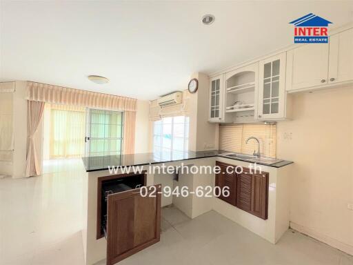 Modern kitchen with upper and lower cabinets, integrated sink, and pass-through window to living area