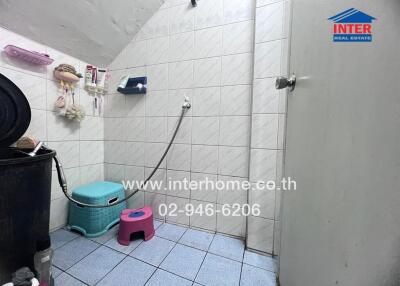 Bathroom with tiled walls and floor, equipped with shower and cleaning supplies