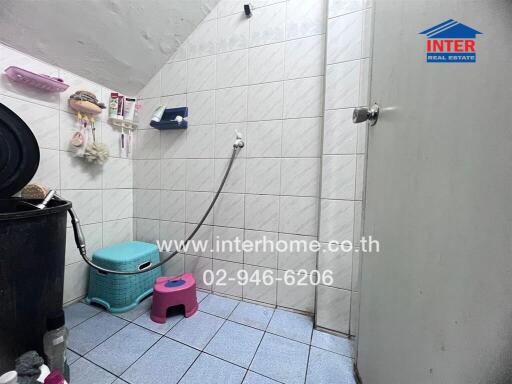 Bathroom with tiled walls and floor, equipped with shower and cleaning supplies