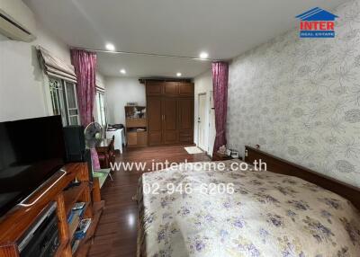 A spacious bedroom with a bed, TV unit, wardrobe, vanity, and air conditioning.