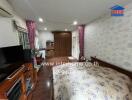 A spacious bedroom with a bed, TV unit, wardrobe, vanity, and air conditioning.