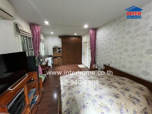 A spacious bedroom with a bed, TV unit, wardrobe, vanity, and air conditioning.