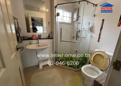 A modern bathroom with a glass shower enclosure, toilet, and sink.