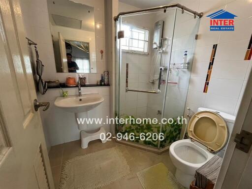 A modern bathroom with a glass shower enclosure, toilet, and sink.