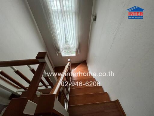 Staircase with wooden steps and white curtains on the window