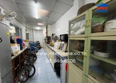 Long kitchen with various appliances and storage shelves